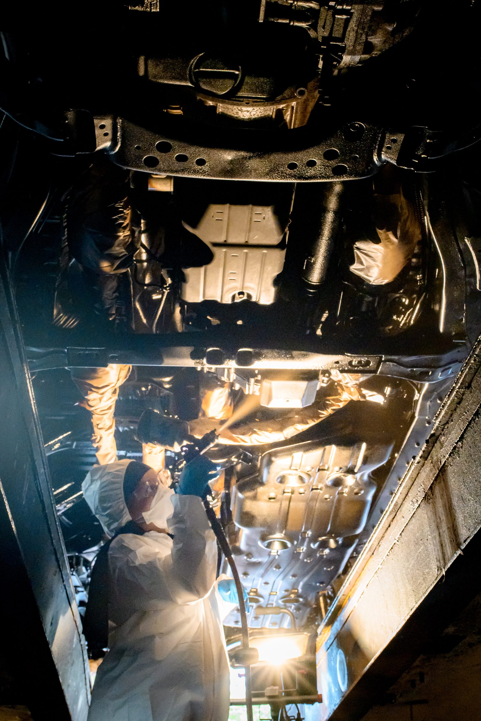 Undercoating being applied to a vehicle floor pan on a lift