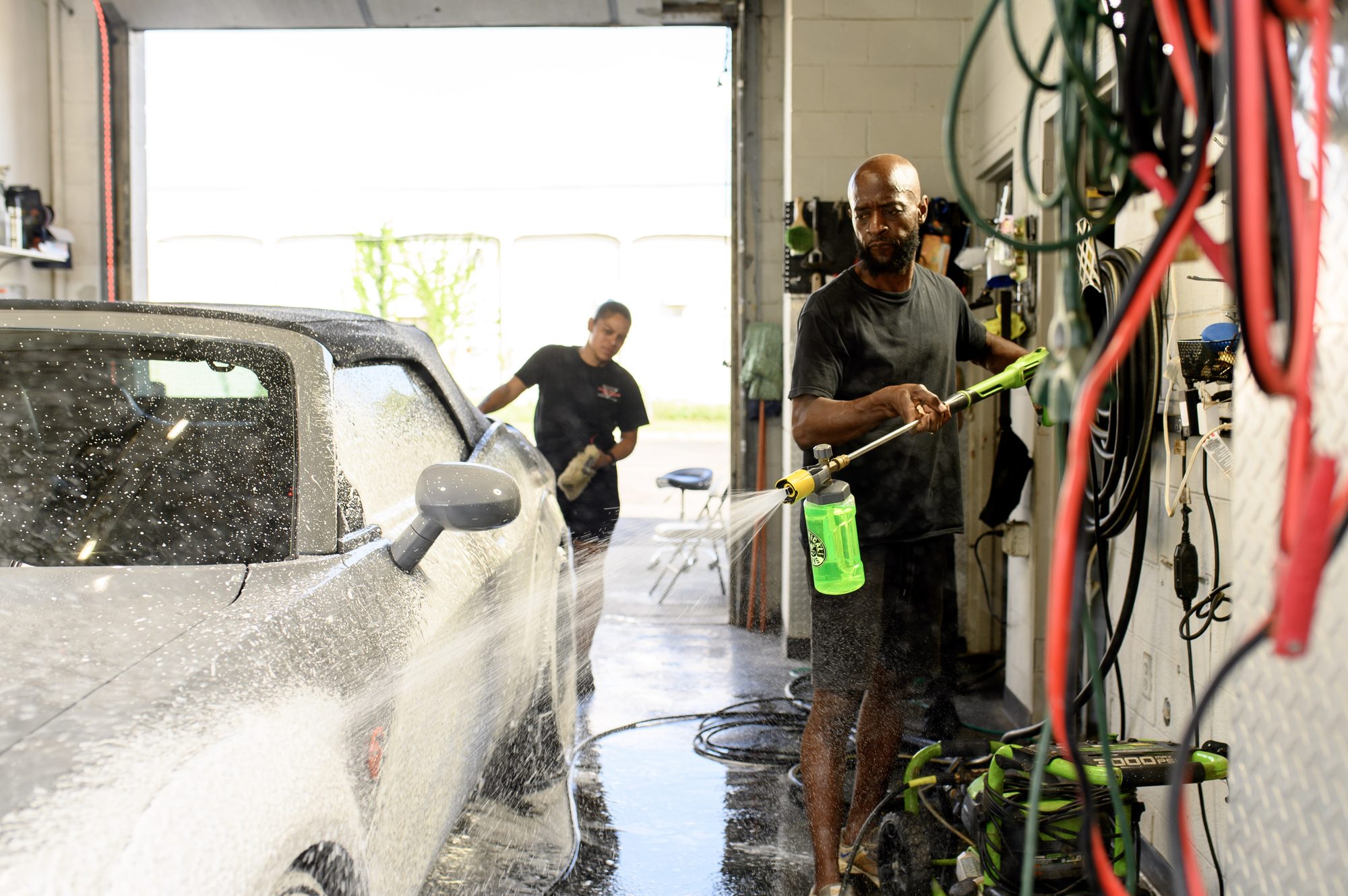 Two staff members washing a car in the Columbus Undercoating wash bay